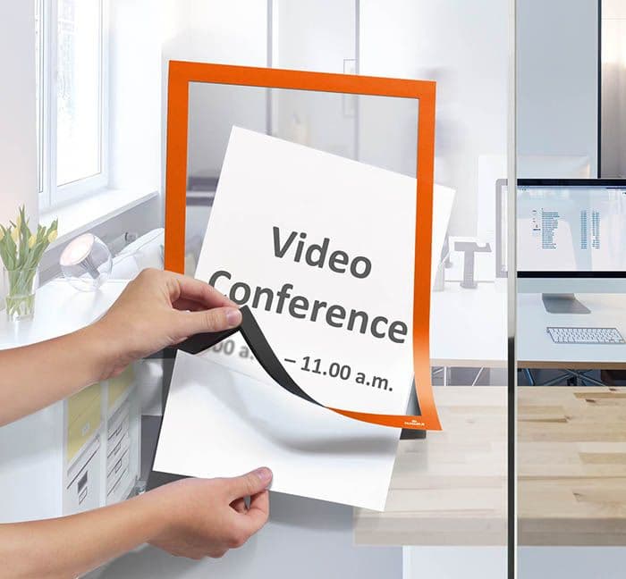 DURAFRAME Info-Rahmen mit Video-Conference Hinweis an einer Glaswand befestigt